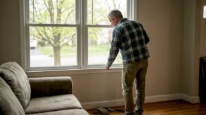 Homeowner examining cracked window in living room